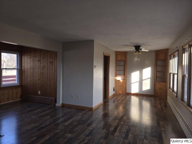 empty room with a baseboard heating unit, dark hardwood / wood-style floors, and ceiling fan