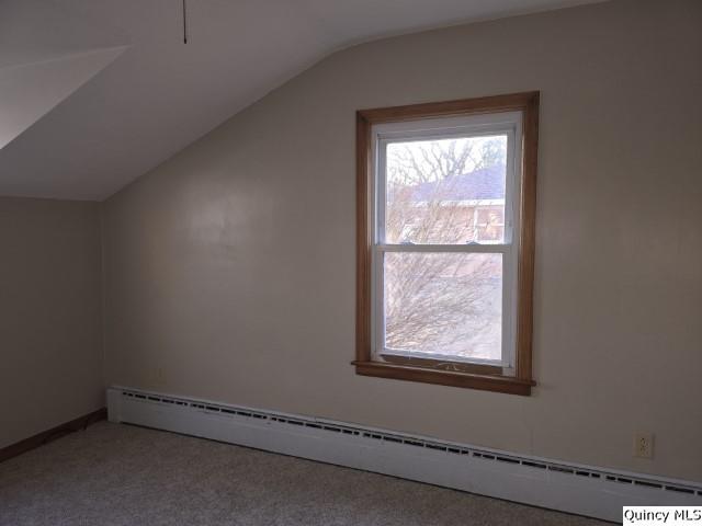 additional living space with a baseboard heating unit, a wealth of natural light, carpet, and vaulted ceiling