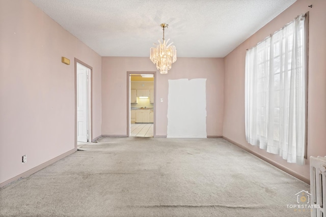 carpeted spare room featuring radiator, an inviting chandelier, and a textured ceiling