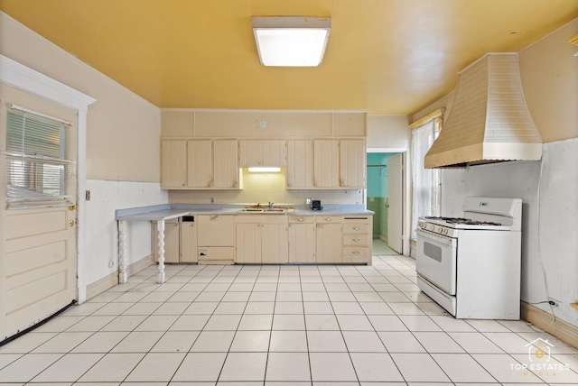 kitchen featuring sink, white gas stove, custom exhaust hood, and light tile patterned floors