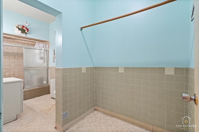 bathroom with radiator heating unit, tile walls, and walk in shower