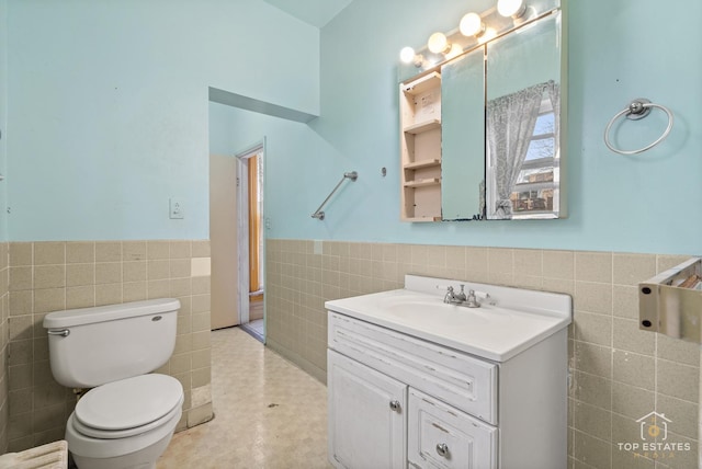 bathroom with tile patterned floors, vanity, toilet, and tile walls