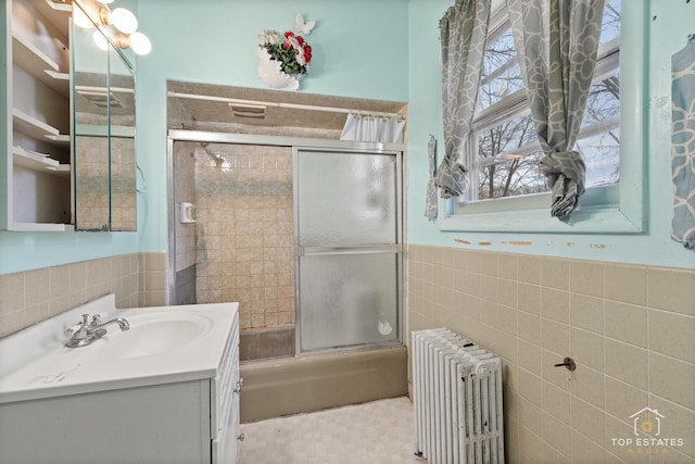 bathroom featuring enclosed tub / shower combo, radiator heating unit, tile walls, and vanity