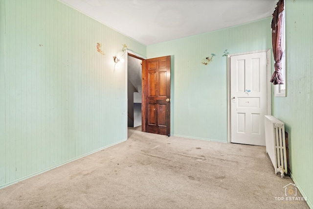 empty room featuring light colored carpet and radiator heating unit