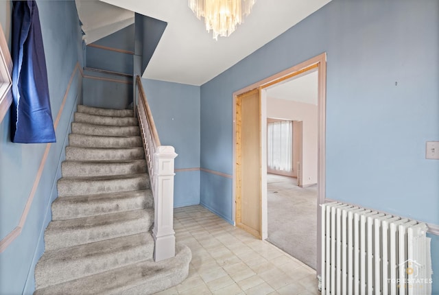 stairs with a notable chandelier, radiator heating unit, and carpet