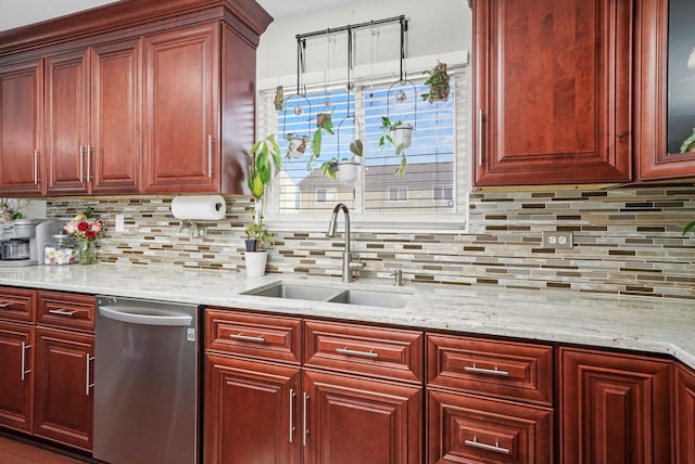 kitchen with light stone countertops, sink, and stainless steel dishwasher