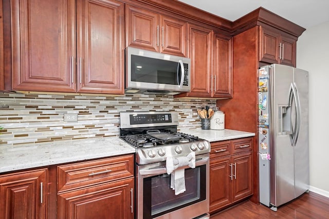 kitchen featuring stainless steel appliances, tasteful backsplash, light stone countertops, and dark hardwood / wood-style flooring