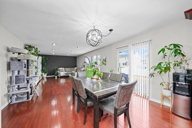 dining area with hardwood / wood-style flooring and an inviting chandelier