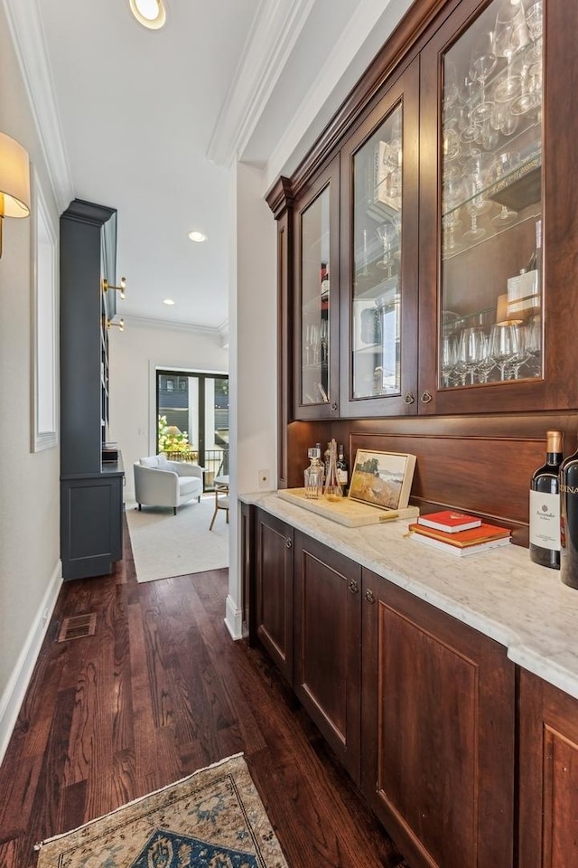 bar with crown molding, light stone countertops, and dark brown cabinets