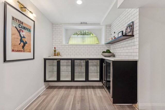 bar featuring light hardwood / wood-style floors and decorative backsplash