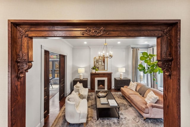 living room featuring an inviting chandelier, hardwood / wood-style floors, crown molding, and plenty of natural light