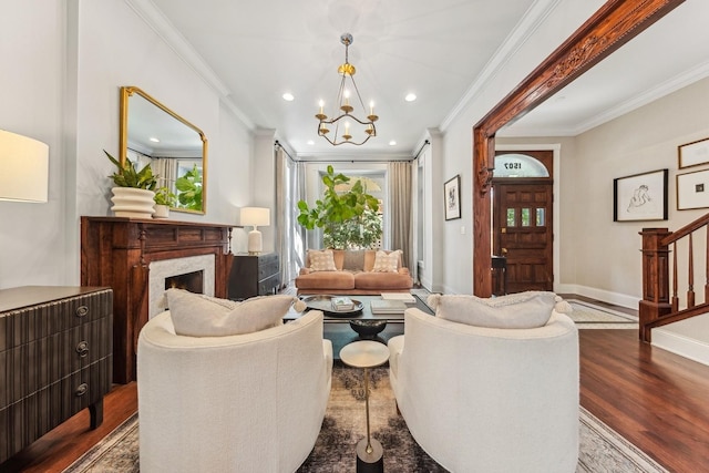 living room with crown molding, hardwood / wood-style flooring, a fireplace, and a chandelier