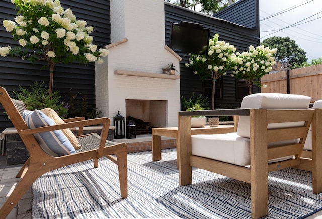 deck featuring an outdoor brick fireplace and a patio