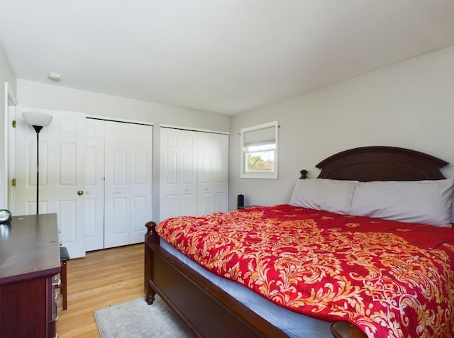 bedroom with multiple closets and light wood-type flooring