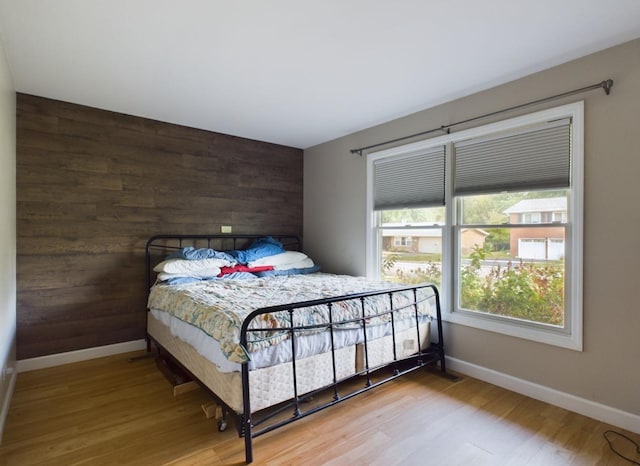 bedroom with wood-type flooring and wooden walls