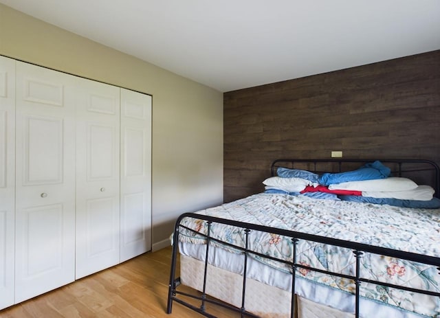 bedroom with hardwood / wood-style floors, wooden walls, and a closet