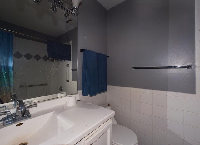 bathroom featuring vanity, toilet, curtained shower, and tile walls