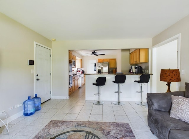 kitchen featuring a breakfast bar, stainless steel fridge with ice dispenser, light tile patterned floors, kitchen peninsula, and ceiling fan