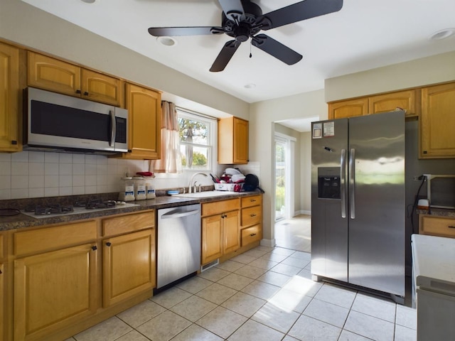 kitchen featuring sink, dark stone countertops, backsplash, light tile patterned floors, and stainless steel appliances