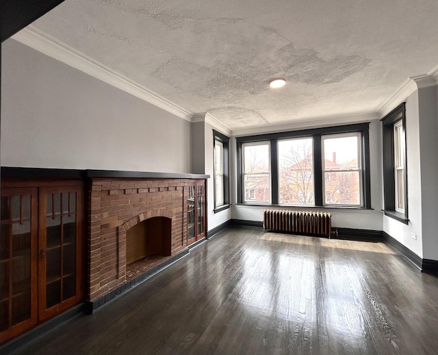 unfurnished living room with radiator, a fireplace, ornamental molding, a textured ceiling, and dark hardwood / wood-style flooring