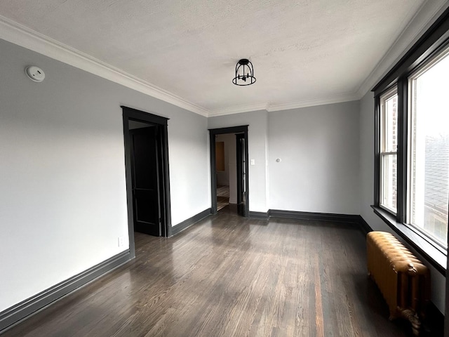 spare room with radiator, crown molding, and dark hardwood / wood-style floors