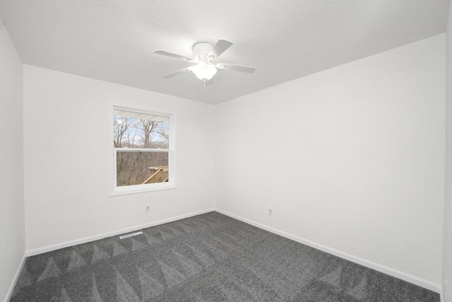 empty room with ceiling fan, a textured ceiling, and dark colored carpet