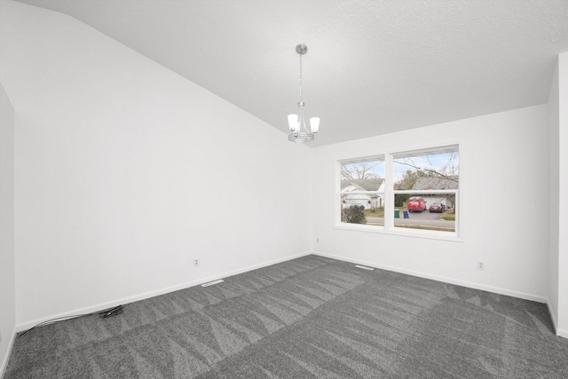 carpeted empty room featuring vaulted ceiling, a textured ceiling, and an inviting chandelier