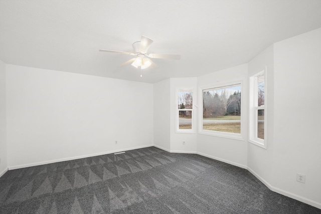 unfurnished room with ceiling fan and dark colored carpet