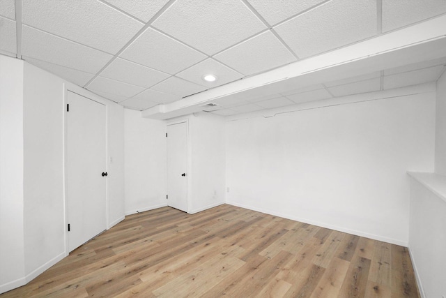 basement with wood-type flooring and a paneled ceiling