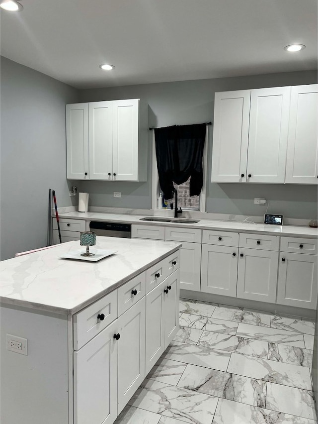 kitchen with white cabinetry, sink, stainless steel dishwasher, and a kitchen island