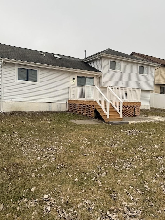 rear view of house with a lawn and a deck