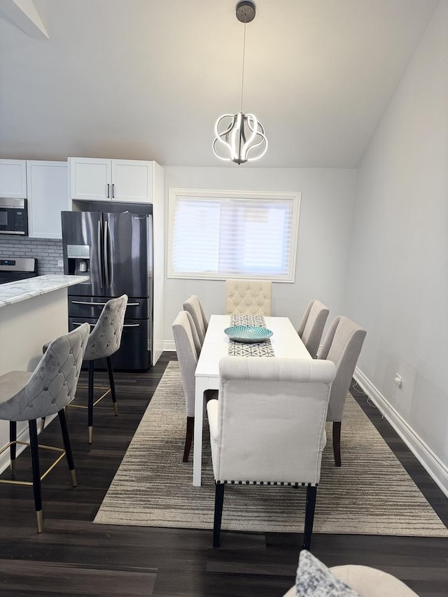 dining area featuring vaulted ceiling, dark hardwood / wood-style floors, and a chandelier