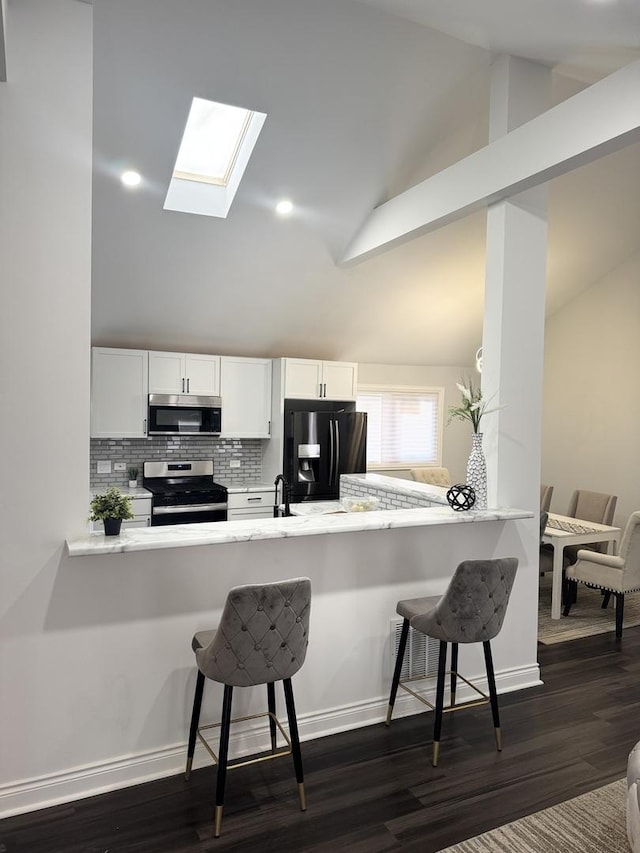 kitchen with white cabinetry, stainless steel appliances, a kitchen breakfast bar, and kitchen peninsula