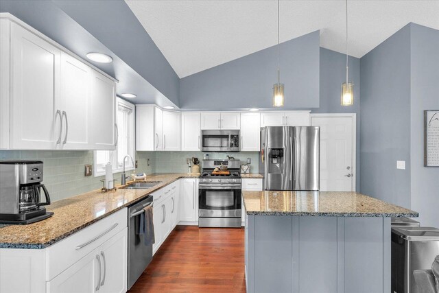 kitchen featuring sink, white cabinetry, light stone counters, decorative light fixtures, and stainless steel appliances