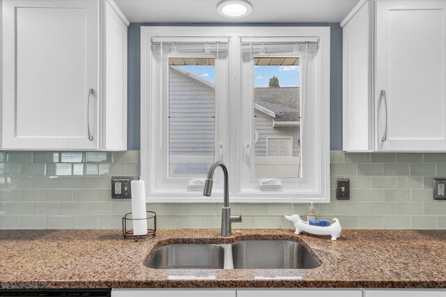 kitchen featuring tasteful backsplash, white cabinetry, sink, and dark stone countertops