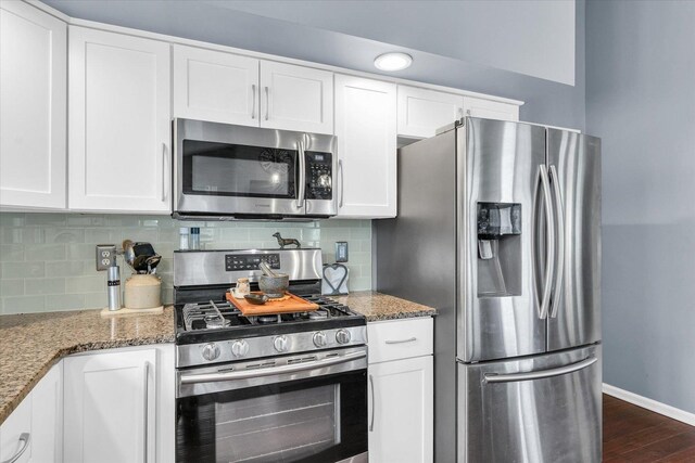 kitchen with tasteful backsplash, white cabinets, stainless steel appliances, and dark stone counters