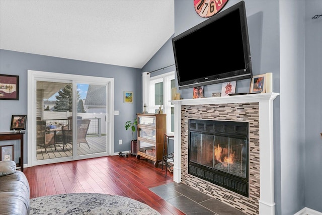 living room featuring a tile fireplace, lofted ceiling, a textured ceiling, and dark hardwood / wood-style flooring