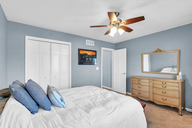 carpeted bedroom featuring a textured ceiling, ceiling fan, and a closet