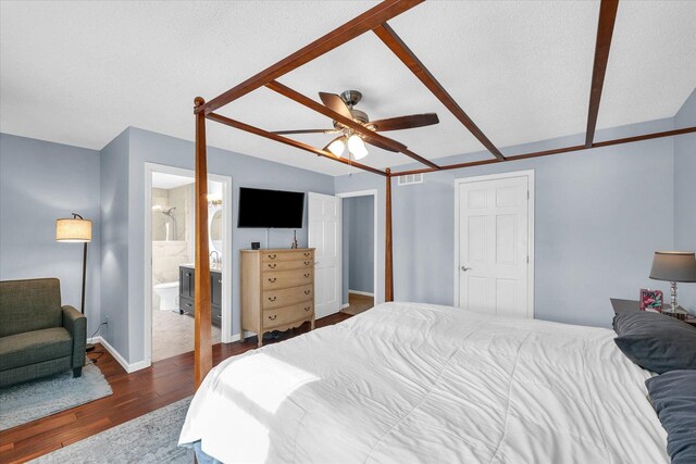 bedroom with ceiling fan, connected bathroom, dark hardwood / wood-style floors, and a textured ceiling