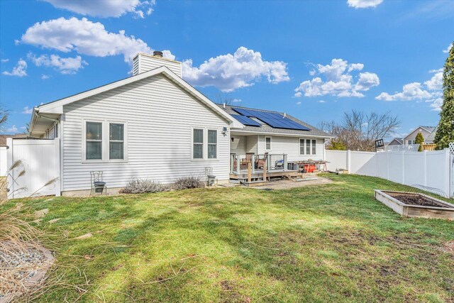 rear view of house featuring a yard, solar panels, and a deck