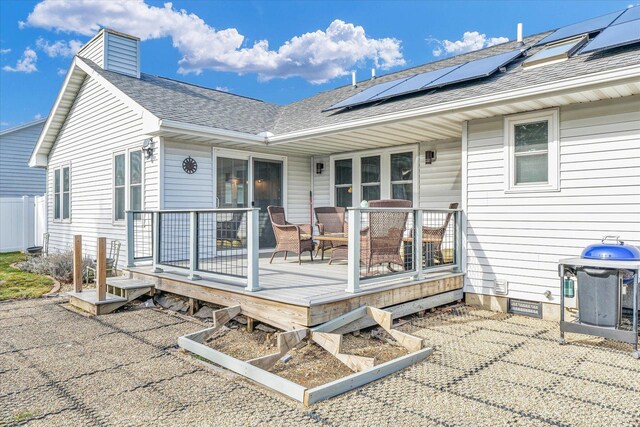 rear view of property with solar panels and a deck