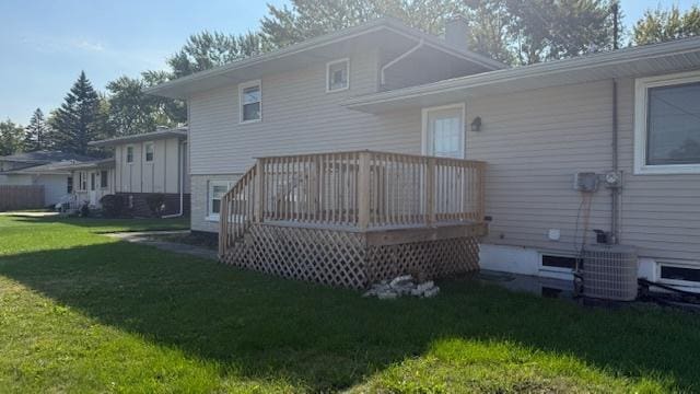 back of house with cooling unit, a deck, and a lawn