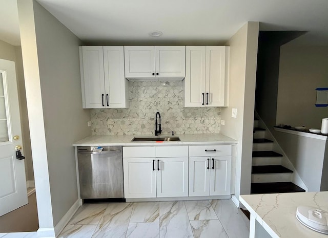 kitchen featuring white cabinetry, sink, stainless steel dishwasher, and light stone counters