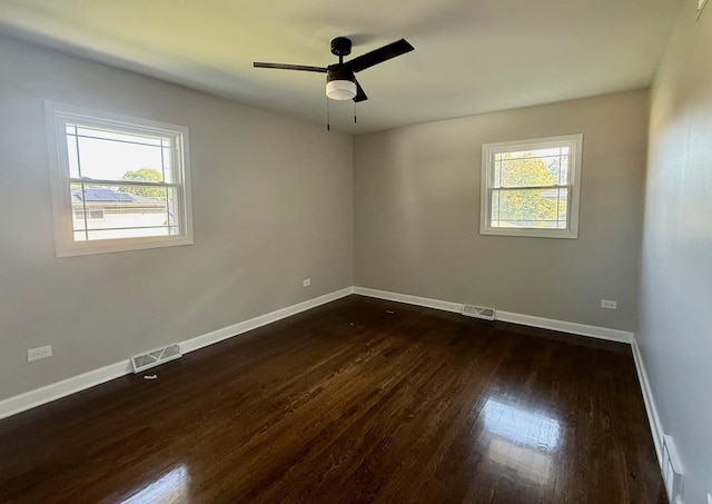 empty room featuring ceiling fan, dark hardwood / wood-style floors, and a healthy amount of sunlight