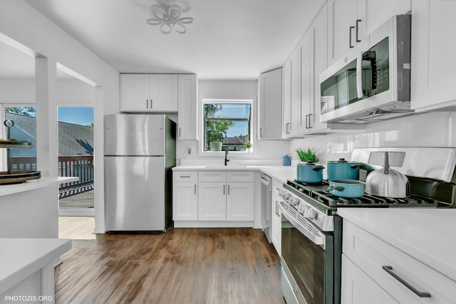 kitchen featuring appliances with stainless steel finishes, dark wood-type flooring, white cabinets, and backsplash