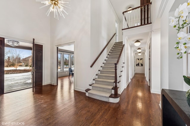 foyer with a towering ceiling, dark hardwood / wood-style floors, and a chandelier