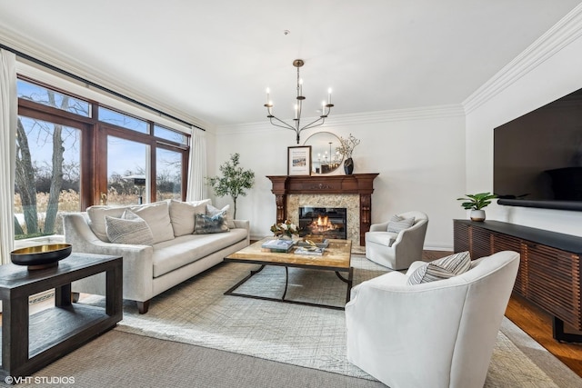 living room featuring crown molding, light wood-type flooring, a chandelier, and a high end fireplace