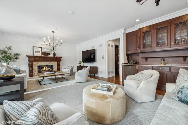 living room with a notable chandelier, crown molding, light hardwood / wood-style flooring, and a premium fireplace