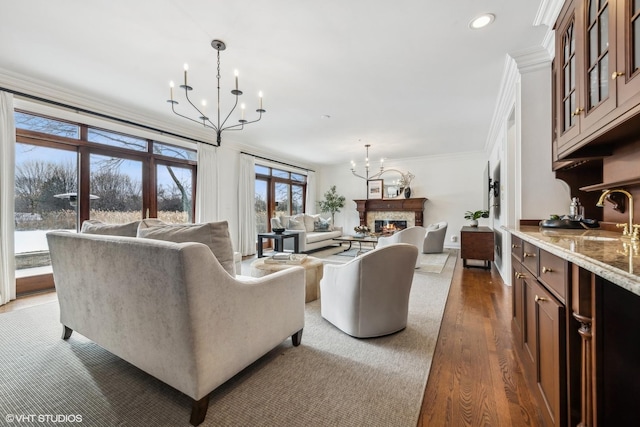 living room with ornamental molding, dark hardwood / wood-style floors, a chandelier, and sink