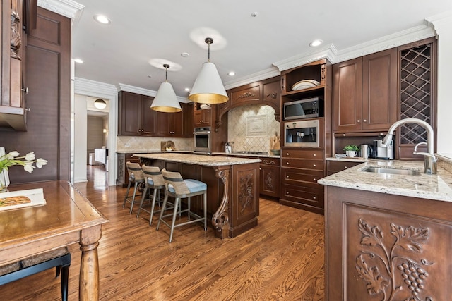 kitchen with dark brown cabinetry, sink, hanging light fixtures, and appliances with stainless steel finishes